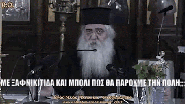 a man with a beard is speaking into a microphone in front of a sign that says " r.o. "