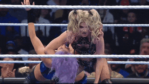 two women are wrestling in a ring with ropes surrounding them