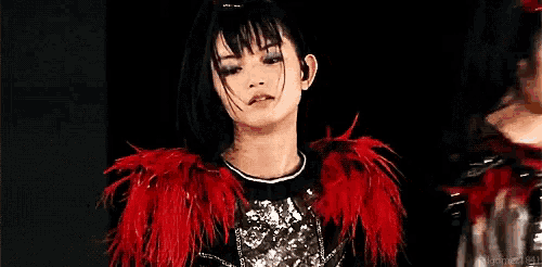the girl is wearing a red feathered jacket and a black shirt .