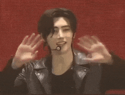 a young man wearing a leather jacket and a microphone is making a funny face .