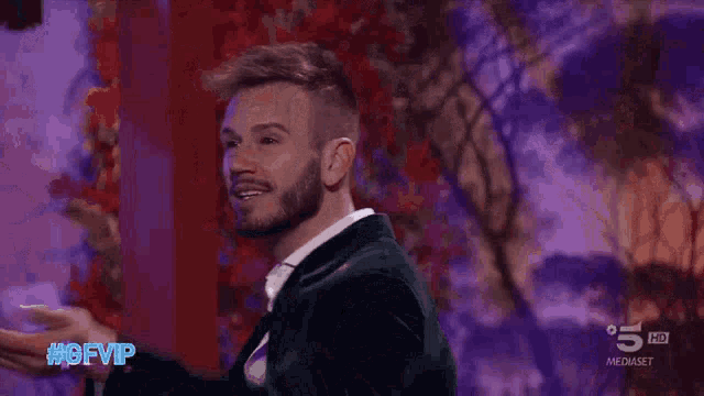 a man in a suit and white shirt is dancing on a stage in front of a purple background ..