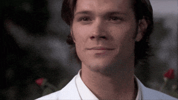 a man wearing a white shirt and a white jacket smiles