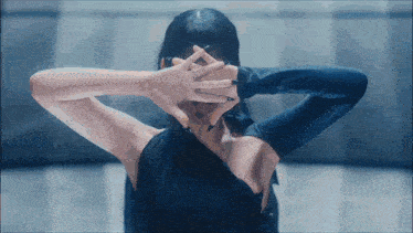 a woman in a black dress is making a heart shape with her hands