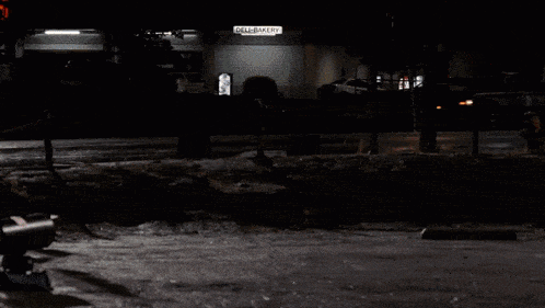 a car is on fire in front of a fence with a sign that says ' a & a ' on it