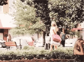 a woman sitting under a tree with a pink purse