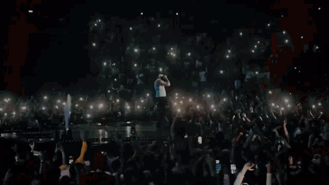 a man is singing into a microphone in front of a crowd .