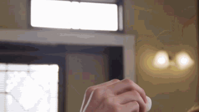 a person is holding a white object in their hands in front of a window