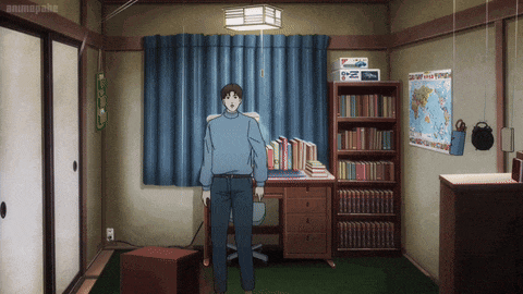 a man in a blue sweater is standing in a room with a map of the world on the wall above him
