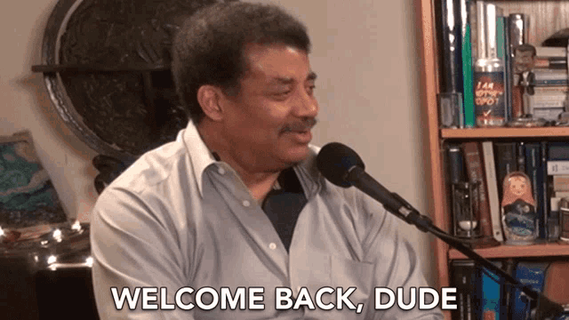 a man sitting in front of a microphone with the words welcome back dude below him