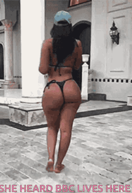 a woman in a bikini is walking in front of a building with the caption she heard bbc lives here .