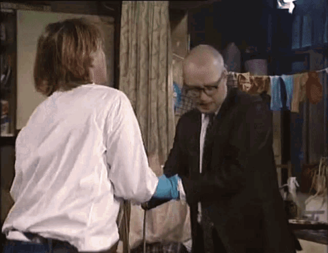 a man in a suit and tie is talking to another man