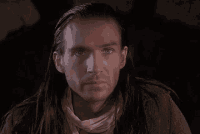 a man with long hair and a white scarf around his neck
