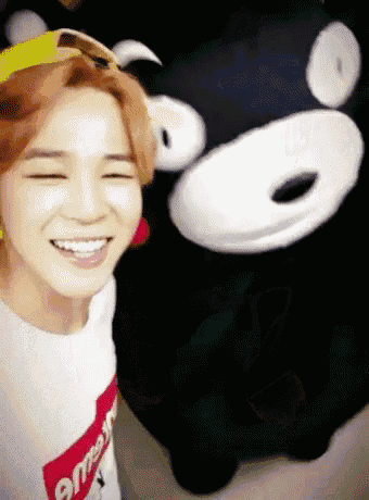 a young man wearing a supreme shirt is smiling next to a stuffed animal .