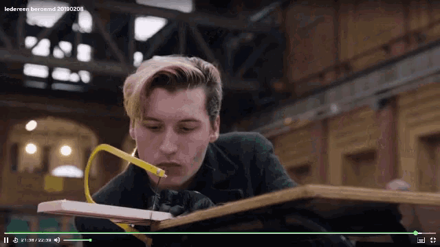 a man is cutting a piece of wood in a video that says ledereen beroend