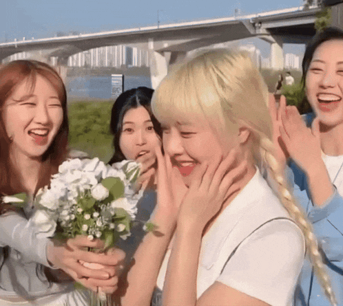 a woman with blonde hair is holding a bouquet of flowers and smiling