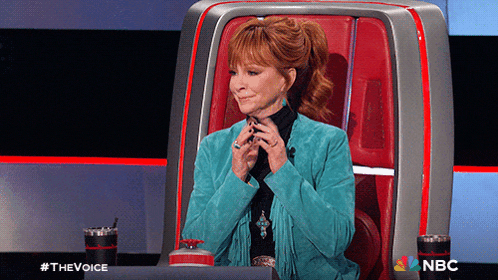 a woman in a blue jacket is sitting in a chair with nbc written on the bottom