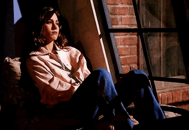 a woman is sitting in front of a window with her arms crossed