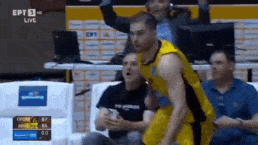 a basketball player is jumping in the air while a referee looks on .