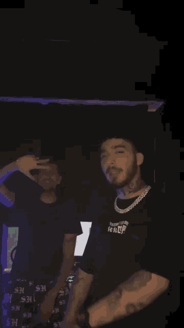 a man with a tattoo on his arm is dancing with another man in a black shirt with the letter h on it