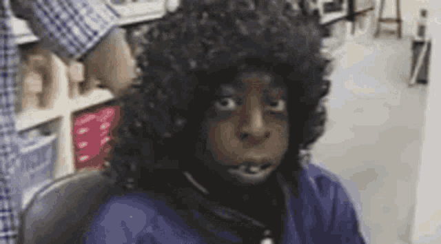 a person wearing a wig is sitting in a chair in a room .