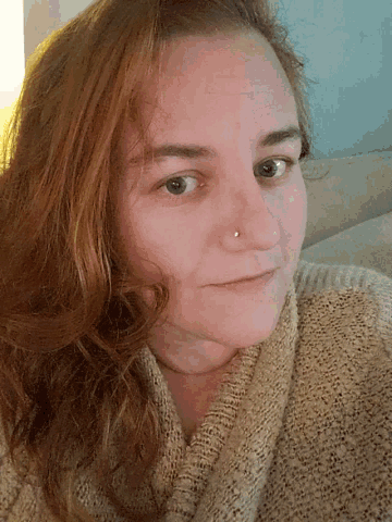 a woman wearing a sweater and a nose ring
