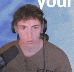 a young man wearing headphones and a microphone is standing in front of a blue background .