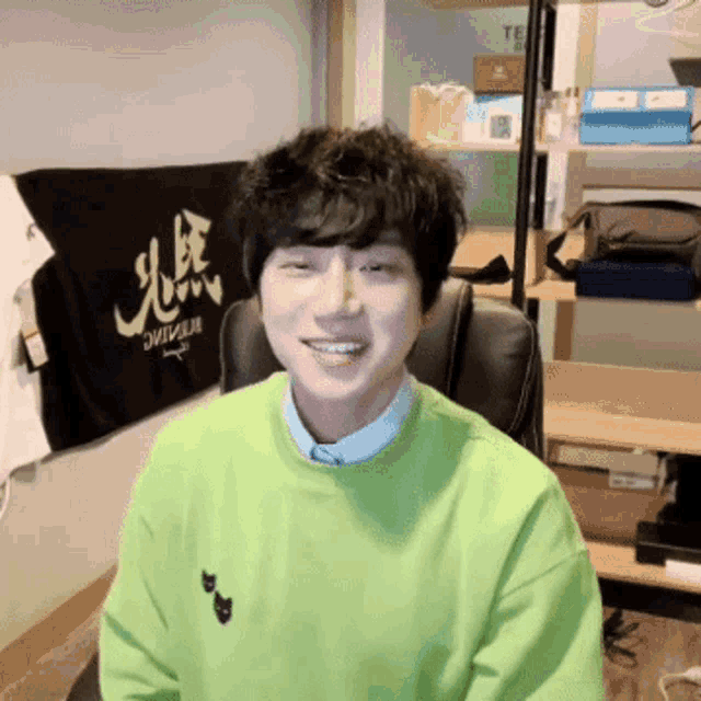 a man wearing a green sweater is smiling in front of a banner that says drive