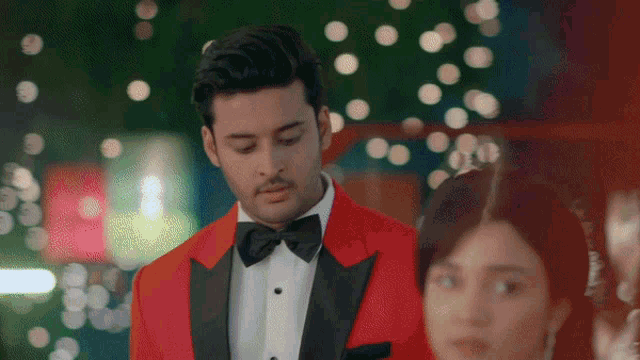 a man in a red tuxedo stands next to a woman in a red dress
