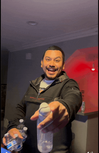 a man wearing a jacket that says helly hansen is holding a bottle of water
