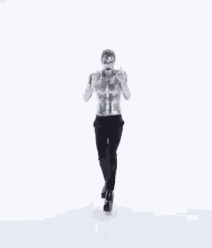 a man without a shirt is standing with his arms outstretched in front of a white background .
