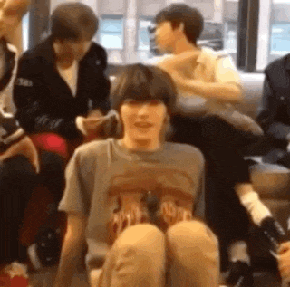 a group of people are sitting on a couch and one of them is sitting on the floor with his legs crossed .