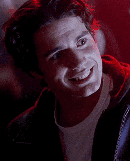a man in a white shirt and a black jacket smiles