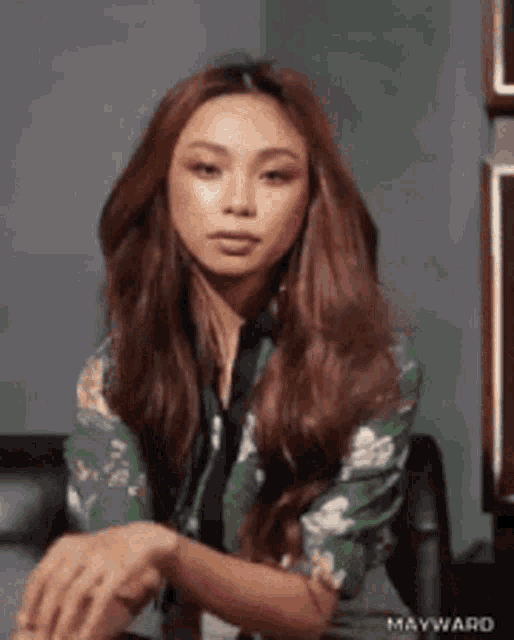 a woman with long hair is wearing a green floral shirt