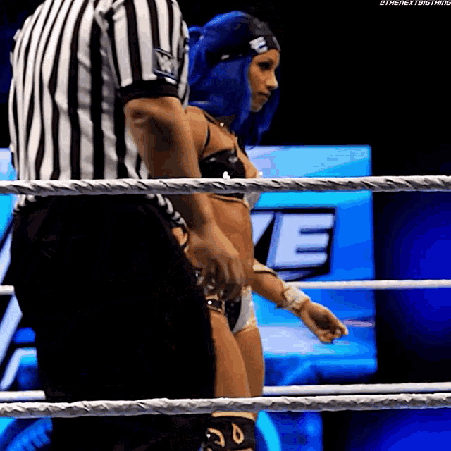 a woman in a bikini is in a wrestling ring with a referee