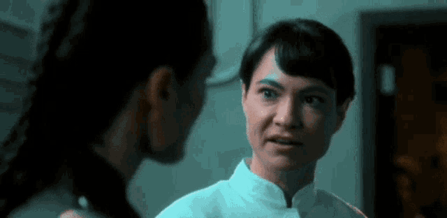 two women are standing next to each other in a dark room and talking to each other .