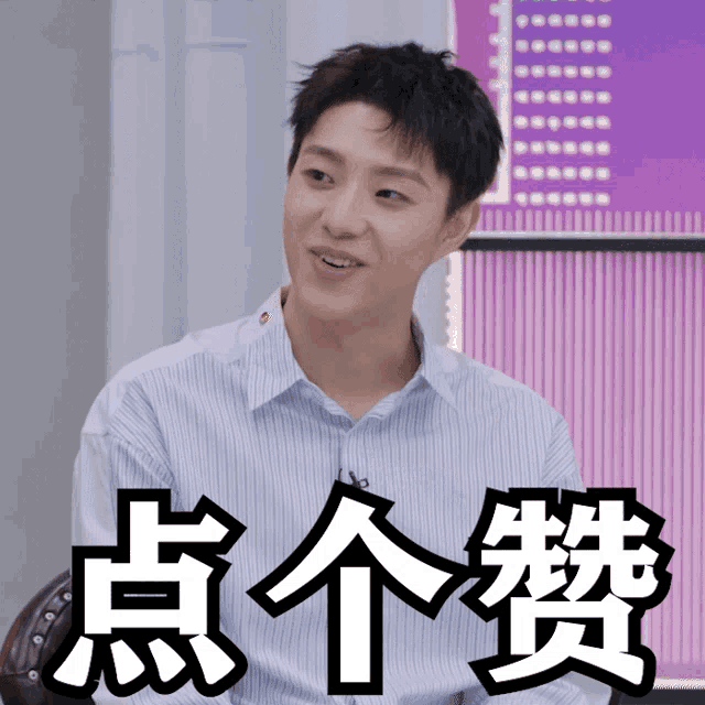 a man in a striped shirt is sitting in front of a purple wall with chinese letters on it