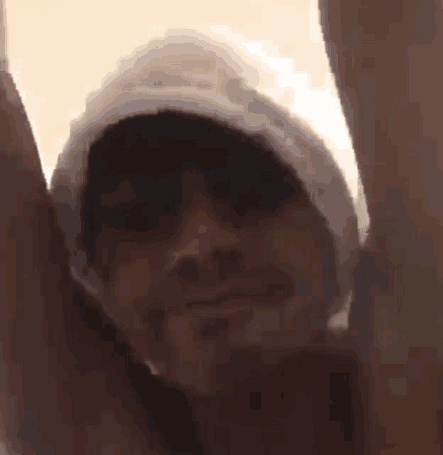 a man wearing a towel and a hat is holding his arms up in the air .