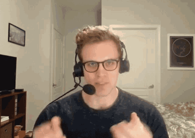a man wearing glasses and a headset with a microphone giving a thumbs up