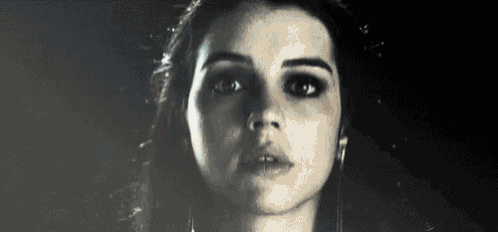 a close up of a woman 's face in a dark room with a black background .