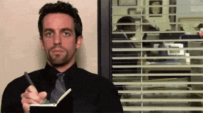 a man in a black shirt and tie is taking notes in a notebook .