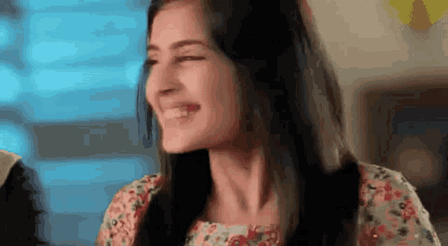 a woman in a floral dress is smiling and laughing .