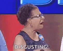 a woman wearing glasses is sitting on a stage with her mouth open and the word disgusting .