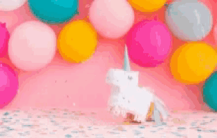a unicorn made out of paper is standing in front of a wall of balloons .
