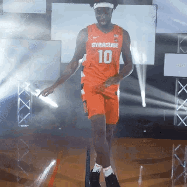a man in an orange syracuse jersey is dancing on a basketball court