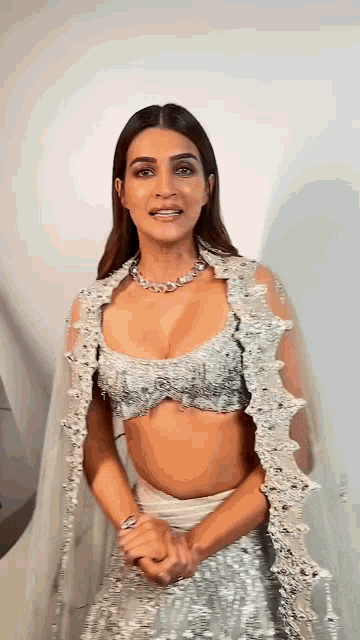 a woman in a crop top and a white skirt is standing in front of a wall .