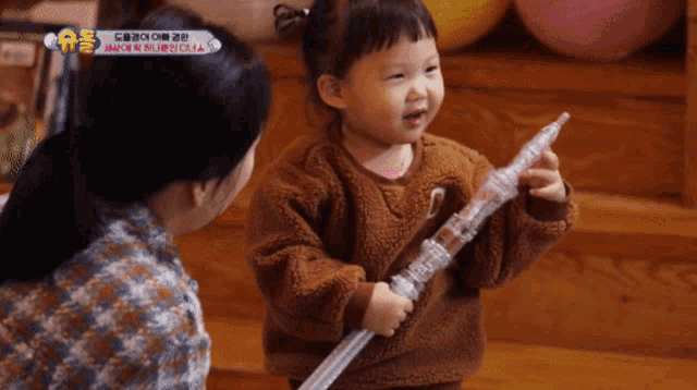 a little girl in a brown sweater is playing with a toy