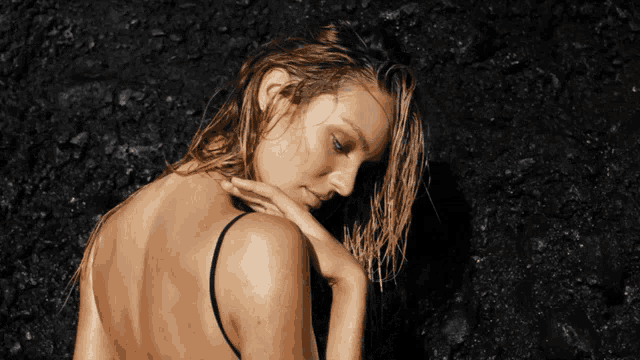 a woman with wet hair and a black top looks down