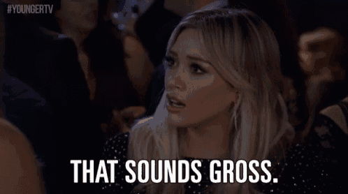 a woman in a black dress is sitting in a crowd and says `` that sounds gross '' .
