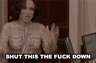 a woman is sitting at a desk in front of a computer and yelling at someone .
