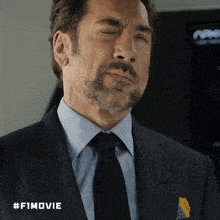 a man in a suit and tie with #fimovie written on the bottom right